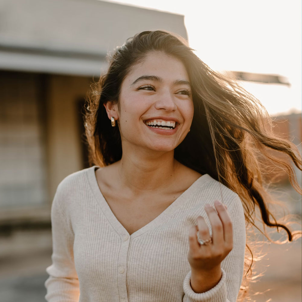 smiling woman in sunset after successful Hybrid Prosthesis treatment from South Lincoln Family Dentistry Dentists of lincoln ne